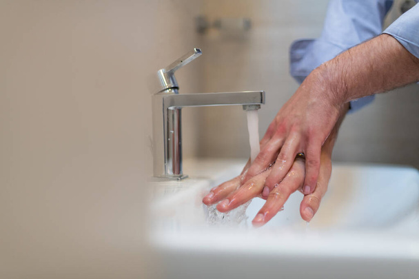 Man using soap and washing hands under the water tap. Hygiene concept hand closeup detail. High quality photo - Foto, immagini