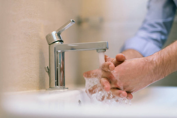 Mna use soap and washing hands under the water tap. Hygiene concept hand detail. High quality photo - Valokuva, kuva