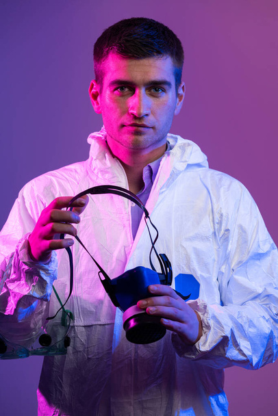Coronavirus covid-19 pandemic. Doctor scientist wearing protective biological suit and mask due to global healthcare epidemic warning and danger background in blue and pink neon lights background - Fotoğraf, Görsel