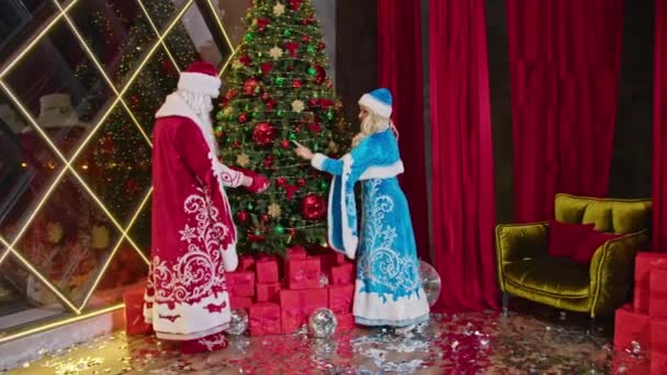 Санта и миссис Санта желают счастливого Рождества, дарят подарки и украшают елку - Кадры, видео