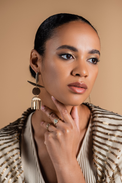 elegant african american woman in golden jewelry touching neck isolated on beige   - Foto, Bild