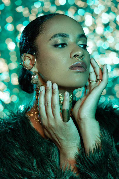african american woman in trendy faux fur jacket and gold on neck on shiny blue background  - Фото, зображення