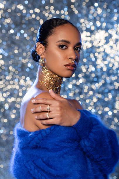 Fashionable african american woman in blue sweater and accessories on sparkling background  - Фото, зображення