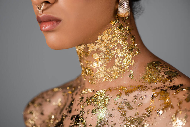 golden foil on neck of cropped african american model isolated on grey  - Foto, Imagen