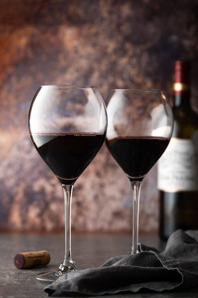 Glasses of red wine with bottle nearby on dark background - Photo, Image