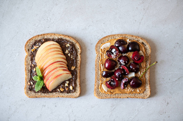Various kind of open sandwiches with berries and fruits. Made from wholegrain bread and different nut butter, such as peanut butter and crunchy cashew or almond butter - Foto, Imagem