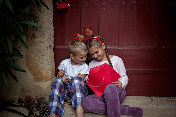 Boldog testvérek viselnek szórakoztató kalap írni egy levelet a Mikulás és álmodozva várja az ajándékokat karácsony este. Téli ünnepek különböző helyeken, Noel hagyomány - Fotó, kép