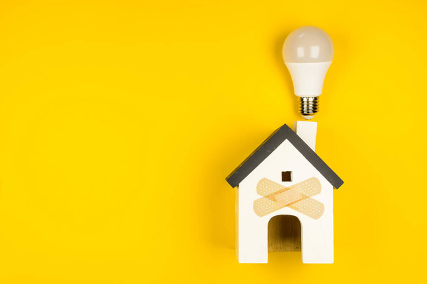 Дерев'яна модель будинку та люксова лампа на жовтому тлі. Концепція, нова ідея, ремонт будинку
. - Фото, зображення