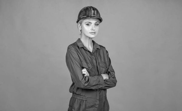 woman architect in protective helmet and boilersuit on orange background, repairman. - Foto, afbeelding