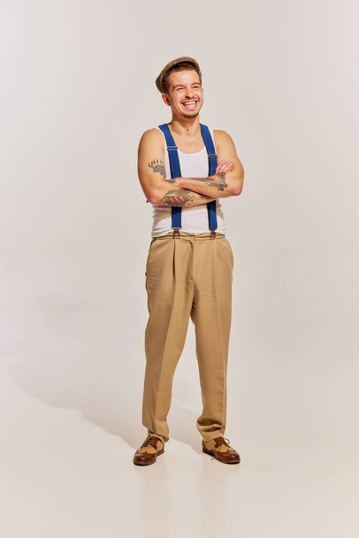Portrait of man in suspenders and pants posing, cheerfully laughing isolated over grey background. Concept of beauty, retro style, fashion, old-fashioned, 60s, 70s, family. Copy space for ad - Φωτογραφία, εικόνα