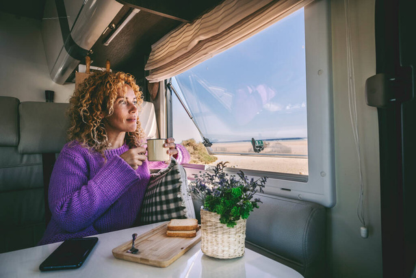 Karavan karavanında yalnız bir kadın açık hava manzaralı otoparklara hayran kalıyor ve evde rahatça çay içiyor. Tatil ve karavan hayatı için seyahat eden insanlar. Telefon tablosu - Fotoğraf, Görsel