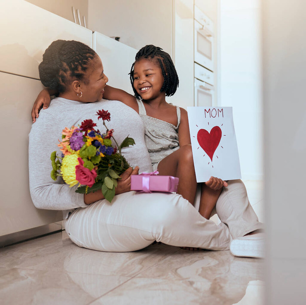 Mother, child and mothers day card and gift with flowers as a gift for loving mom at home. Family, children and daughter with present for love, care and affection for female parent with note. - Фото, изображение