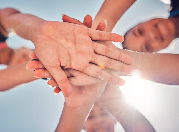 Hands, teamwork and collaboration of friends, community or people together for charity, support and motivation outdoor with lens flare. Group together for trust, commitment and synergy from below. - Foto, imagen