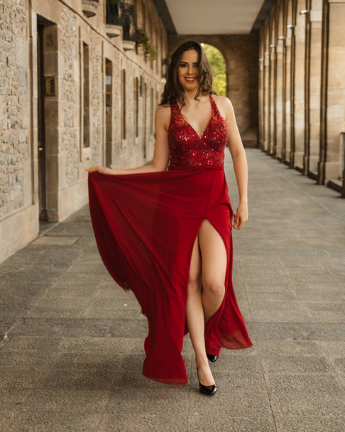 Caucasian woman in a red gala dress, model walking towards the camera - Fotó, kép