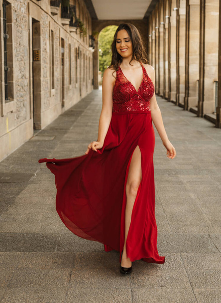 Caucasian woman in a red gala dress, model smiling walking towards the camera - Photo, Image