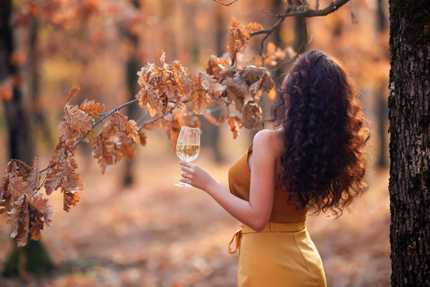 beautiful woman with long hair with a glass of wine in her hand autumn during autumn - Valokuva, kuva