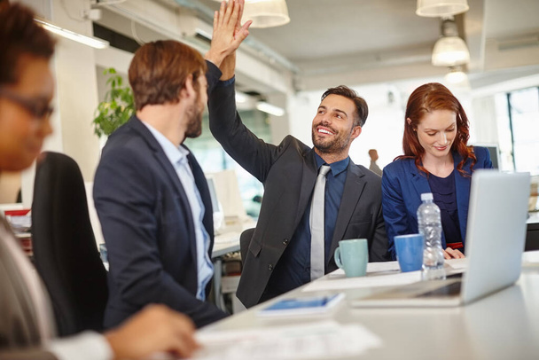Winners win with teamwork. colleagues giving each other a high five during a meeting at work - Фото, зображення