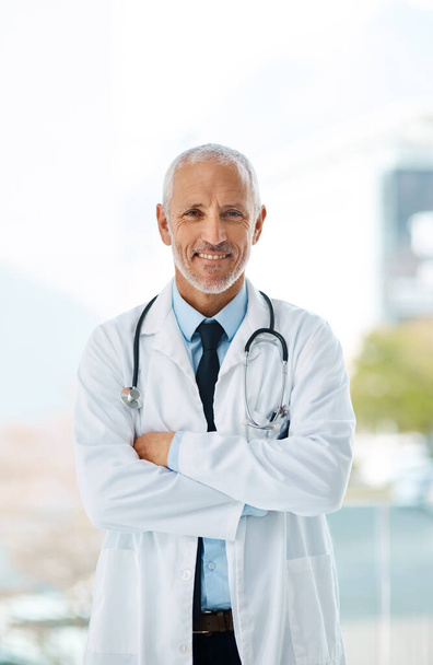 Im the doctor wholl take care of all your symptoms. a mature male doctor standing with his arms crossed - Photo, image