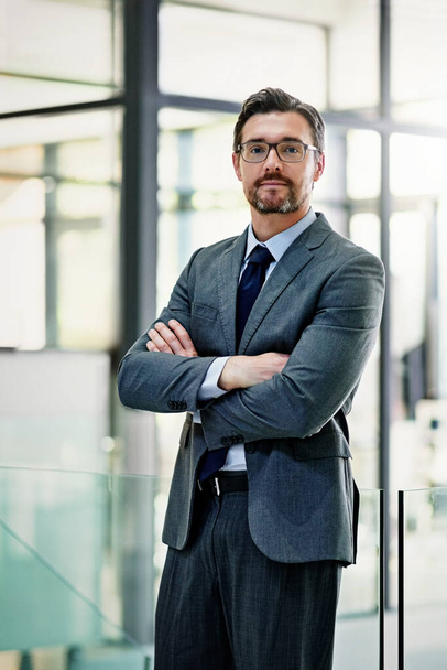 Success follows confidence. Portrait of a mature businessman standing with his arms folded in the office - Foto, Bild
