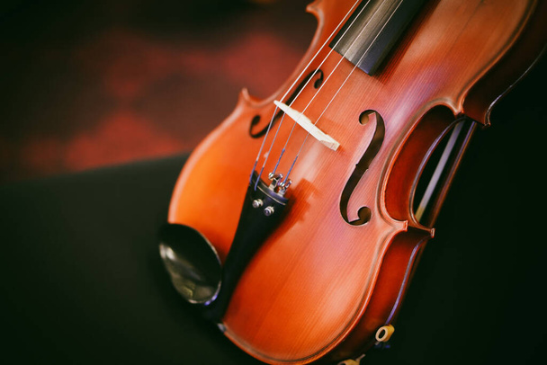 Detail view of a violin on a black chair. - Zdjęcie, obraz