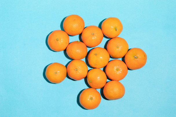 Сочные и здоровые мандарины, грязные, на синем фоне, формирующие образ поп-арта - Фото, изображение