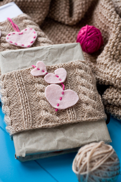 Two old pads in knitted cover with felt hearts lie next to the c - Photo, Image