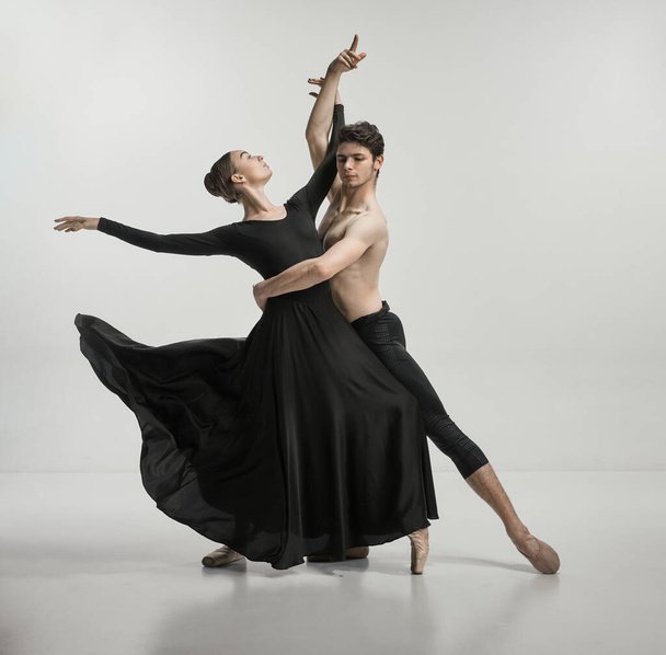 Young man and woman, ballet dancers performing isolated over grey studio background Tenderness and passion. Concept of classical dance aesthetics, choreography, art, beauty. Copy space for ad - Photo, Image