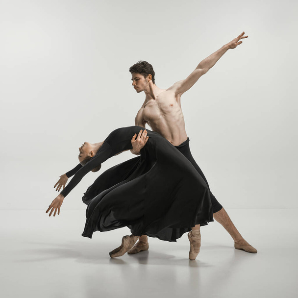 Young man and woman, ballet dancers performing on stage isolated over grey studio background. Lightness and freedom. Concept of classical dance aesthetics, choreography, art, beauty. Copy space for ad - Fotoğraf, Görsel