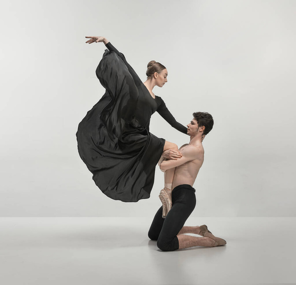 Young man and woman, ballet dancers performing isolated over grey studio background. Support. Beautiful wave. Concept of classical dance aesthetics, choreography, art, beauty. Copy space for ad - Foto, immagini
