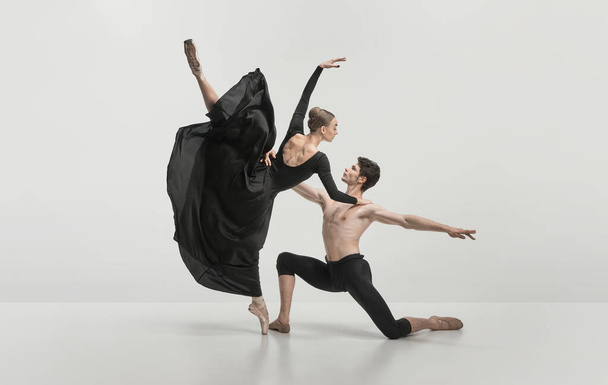 Young man and woman, ballet dancers performing isolated over grey studio background. Noble, pride dance. Concept of classical dance aesthetics, choreography, art, beauty. Copy space for ad - Photo, Image