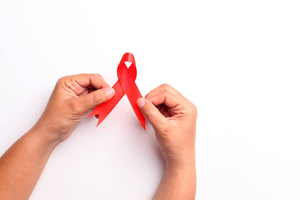 Close up photo of woman's hand holding red ribbon over white background with copyspace. Aids day concept - Photo, Image