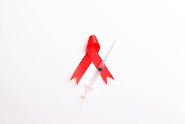 Medical syringe and red ribbon over white background. Aids day concept - Photo, Image