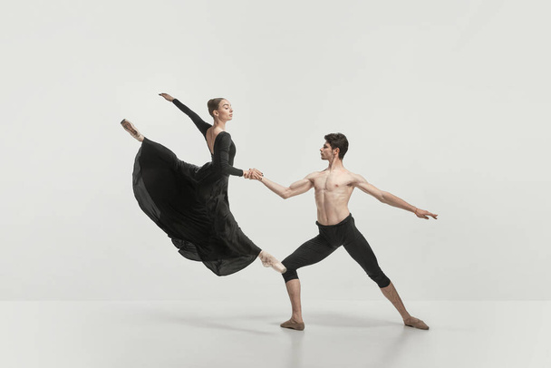 Young man and woman, ballet dancers performing isolated over grey studio background. Flying high. Concept of classical dance aesthetics, choreography, art, beauty. Copy space for ad - Foto, imagen