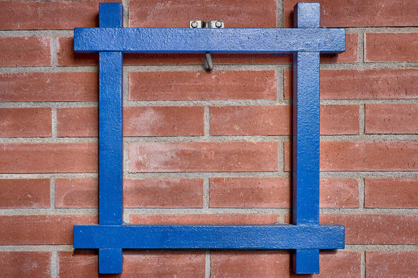Niebieska drewniana rama zawieszona na odsłoniętej ceglanej ścianie z pustym miejscem na tekst - Zdjęcie, obraz