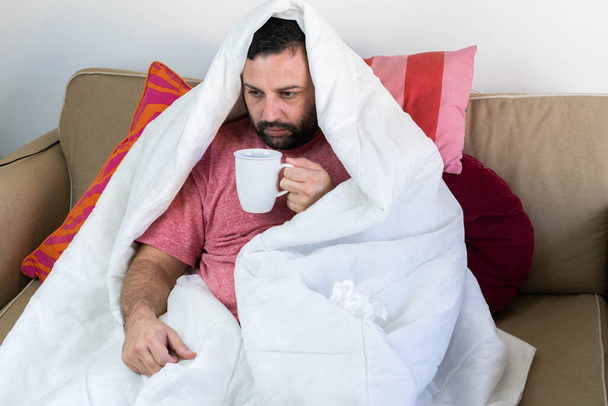 Zieke man met griep en coronavirus bedekt met de deken - Foto, afbeelding