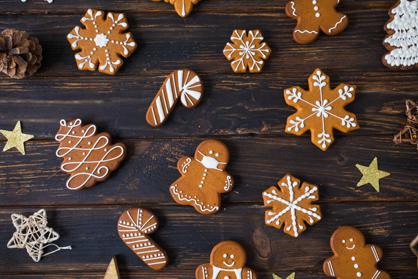 Christmas cookies of various shapes with sugar decor glaze on the wooden table, flat lay with decor - Фото, изображение