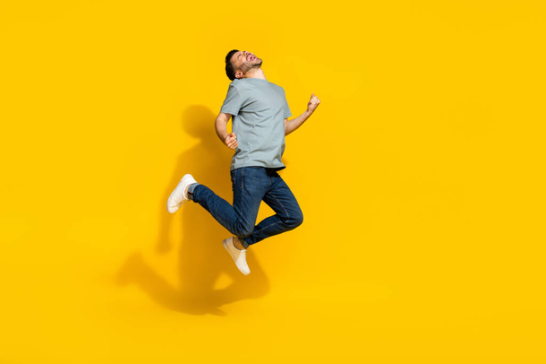 Full body photo of satisfied glad person jumping raise fists scream yes isolated on yellow color background. - Fotó, kép