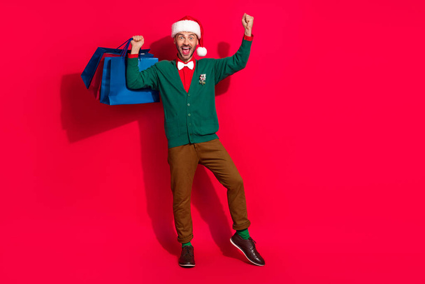 Full length photo of excited lucky guy dressed xmas green cardigan getting noel gifts shoppers empty space isolated red color background. - Valokuva, kuva