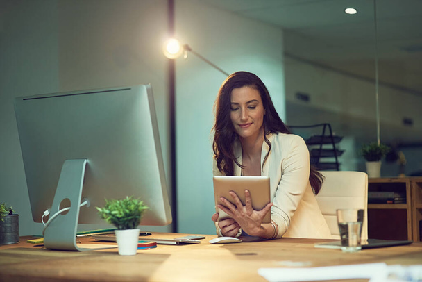 Wir arbeiten hart daran, den Erfolg einzuholen. eine junge Geschäftsfrau arbeitet spät an einem digitalen Tablet in einem Büro - Foto, Bild