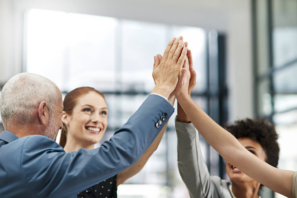Celebrating success. Closeup shot of a group of businesspeople high fiving together in a modern office - Foto, imagen