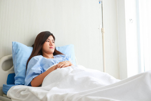 Aziatische vrouwelijke patiënt gestrest en bezorgd Liggen op het bed in de patiëntenkamer. Het begrip ziektekostenverzekering. Medische diensten in ziekenhuizen - Foto, afbeelding