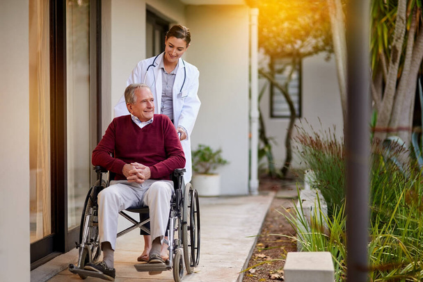 Ele adora uma viagem pelo jardim. um homem idoso em uma cadeira de rodas sendo assistido por uma enfermeira fora de uma clínica - Foto, Imagem