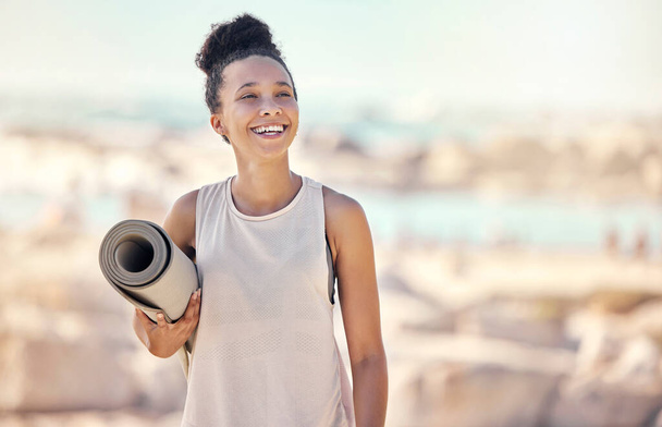 Yoga, fitness en strand zwarte vrouw denken aan meditatie of zen levensstijl in de zomer zonneschijn voor outdoor genezing, wellness en rust. Pilates, sport en gezonde vrouw met trainingsmateriaal aan zee. - Foto, afbeelding