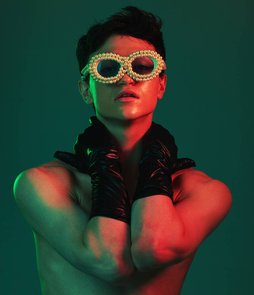 Fashion, model and accessories of a gen z, stylish and fashion model man with glasses aesthetic. Portrait of beauty, designer sunglasses and luxury gloves inspiration looking cool with red light. - Photo, Image