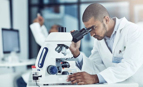 Taking a closer look. a young male scientist working in his lab - Foto, Bild