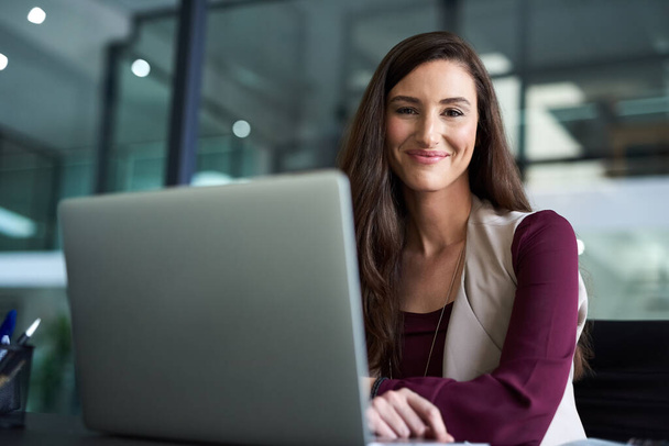 A explorar o potencial dos internets para ganhar dinheiro. uma mulher de negócios sentada em sua mesa com seu laptop - Foto, Imagem