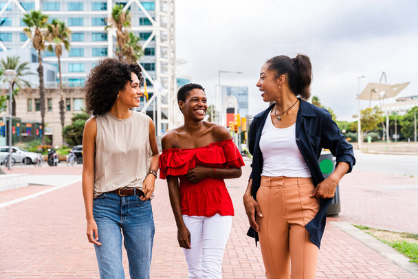 Happy beautiful hispanic south american and black women meeting outdoors and having fun - Black adult females friends spending time together and walking in the city for shopping - Photo, image