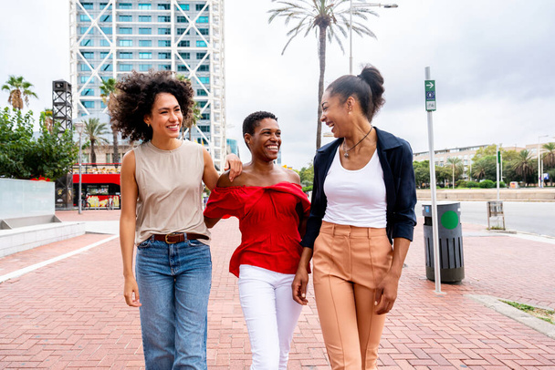 Happy beautiful hispanic south american and black women meeting outdoors and having fun - Black adult females friends spending time together and walking in the city for shopping - Φωτογραφία, εικόνα