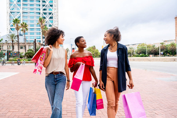 Glücklich schöne hispanische südamerikanische und schwarze Frauen treffen sich draußen und haben Spaß - Schwarze erwachsene Freundinnen verbringen Zeit miteinander und gehen in der Stadt einkaufen - Foto, Bild