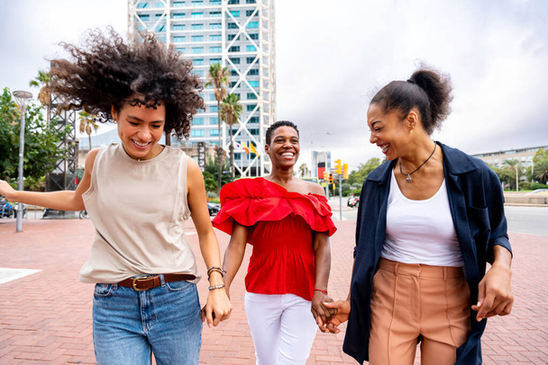 Happy beautiful hispanic south american and black women meeting outdoors and having fun - Black adult females friends spending time together and walking in the city for shopping - Zdjęcie, obraz